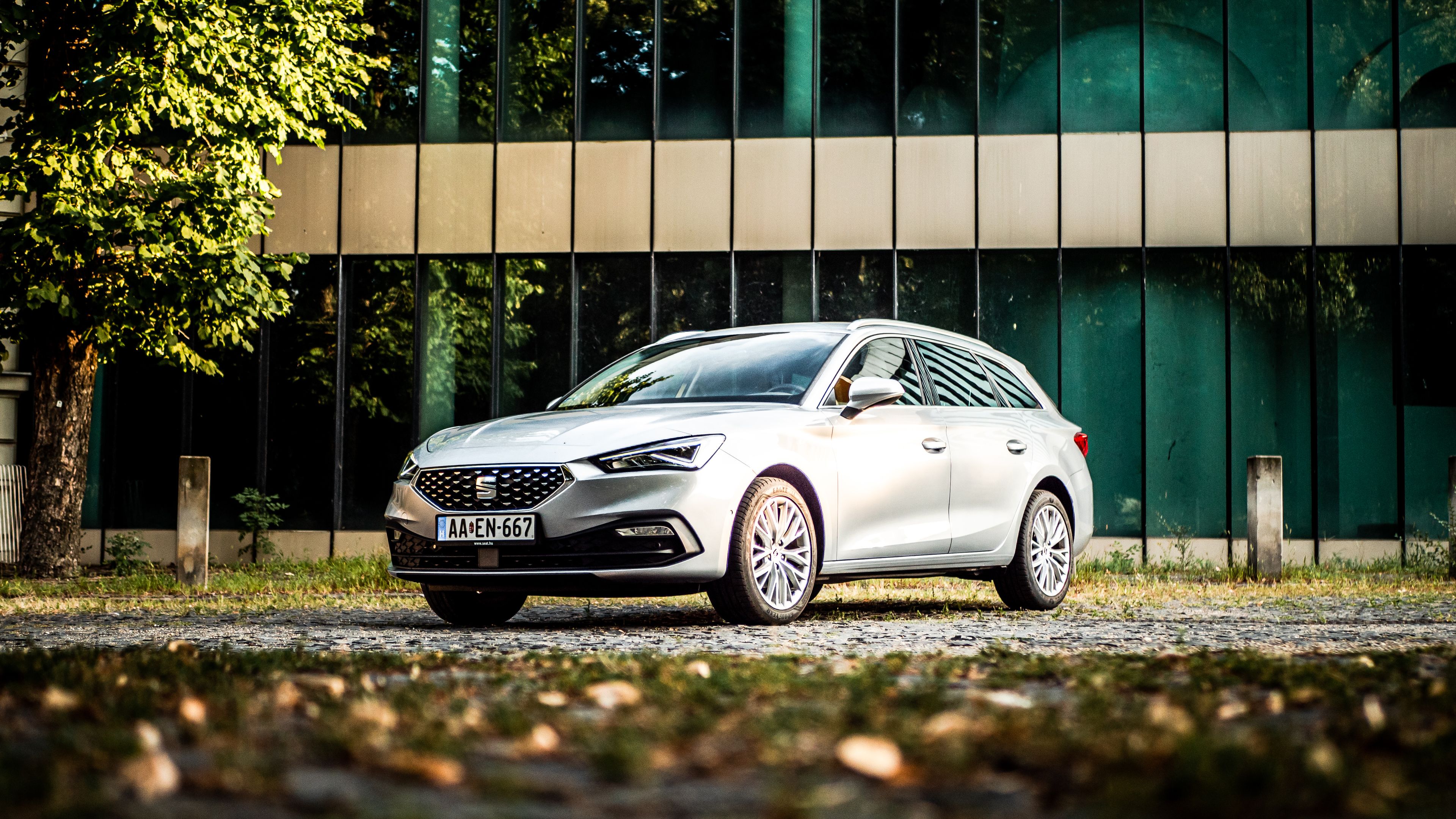 SEAT Leon kombi egy üvegépület előtt ősszel