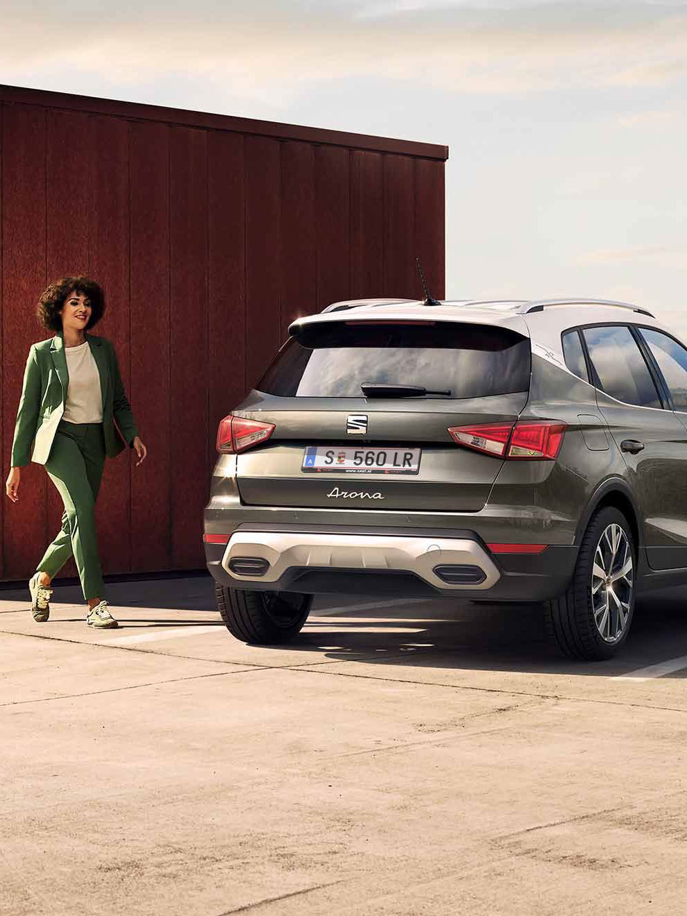 Egy nő sétál el egy SEAT Arona mögött