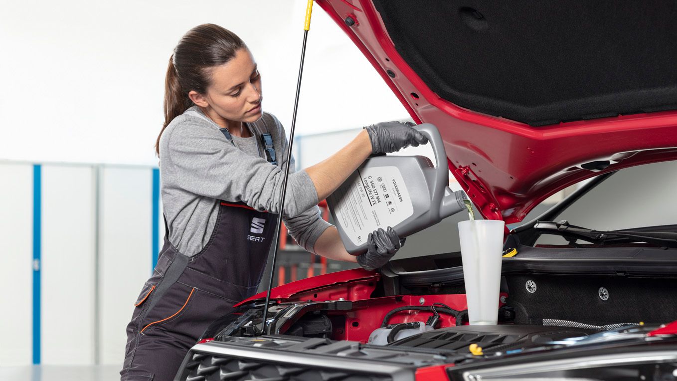 Női szerelő motorolajat tölt egy Seat modellbe